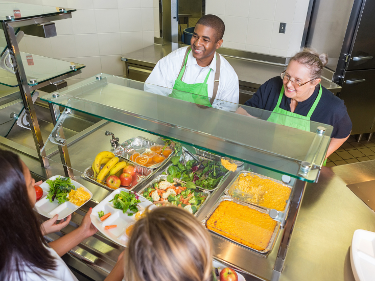 School food service staff serving lunch to students