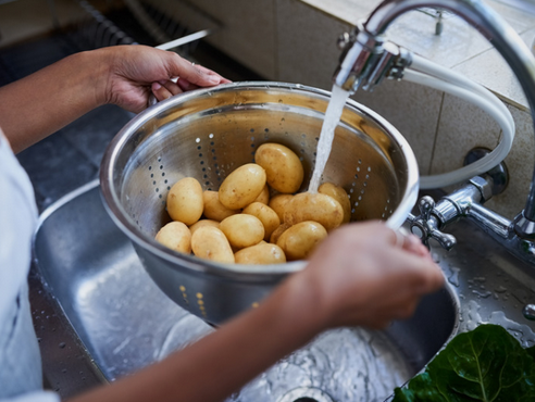 Potatoes being washed in a kitchen sink